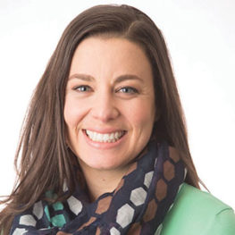 Best Place to Work announcement makes Sr. VP of Programming and Evaluation smile. She is wearing a green shirt and a scarf.