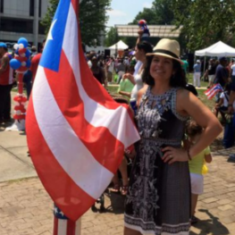 Coach Lisa Keller, a proud Latina, standing with the Puerto Rico flag for National Hispanic Heritage Month.