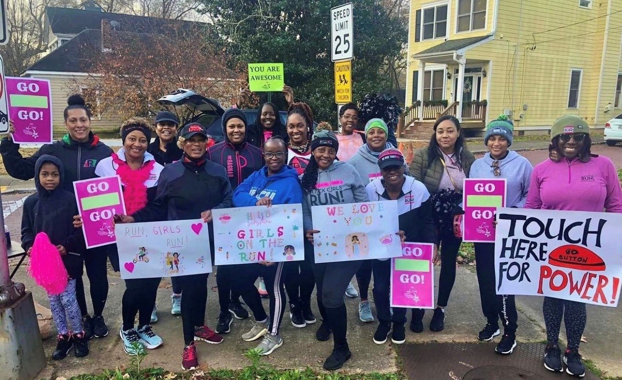 Large group of people in winter clothing holding up their fantastic 5K signs that encourage girl runners