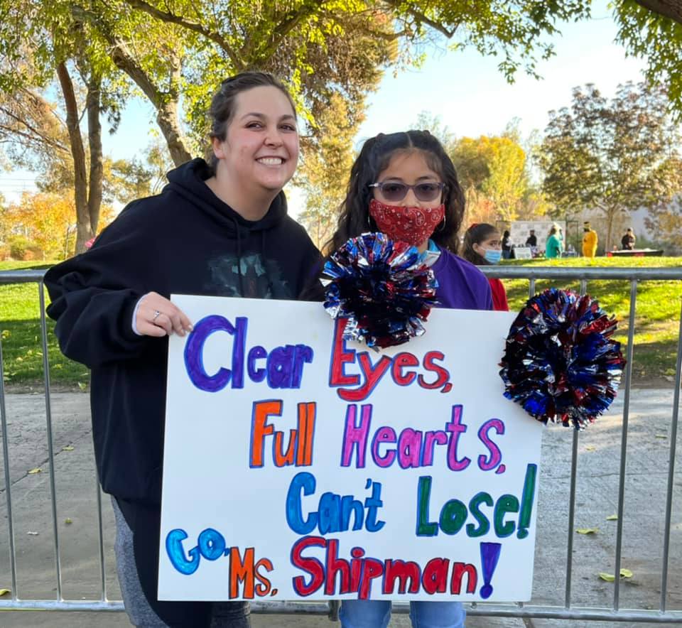 Smiling woman and girl in mask holding up a fantastic 5K sign that says clear eyes, full hearts, can't lose! Go Ms. Shipman!