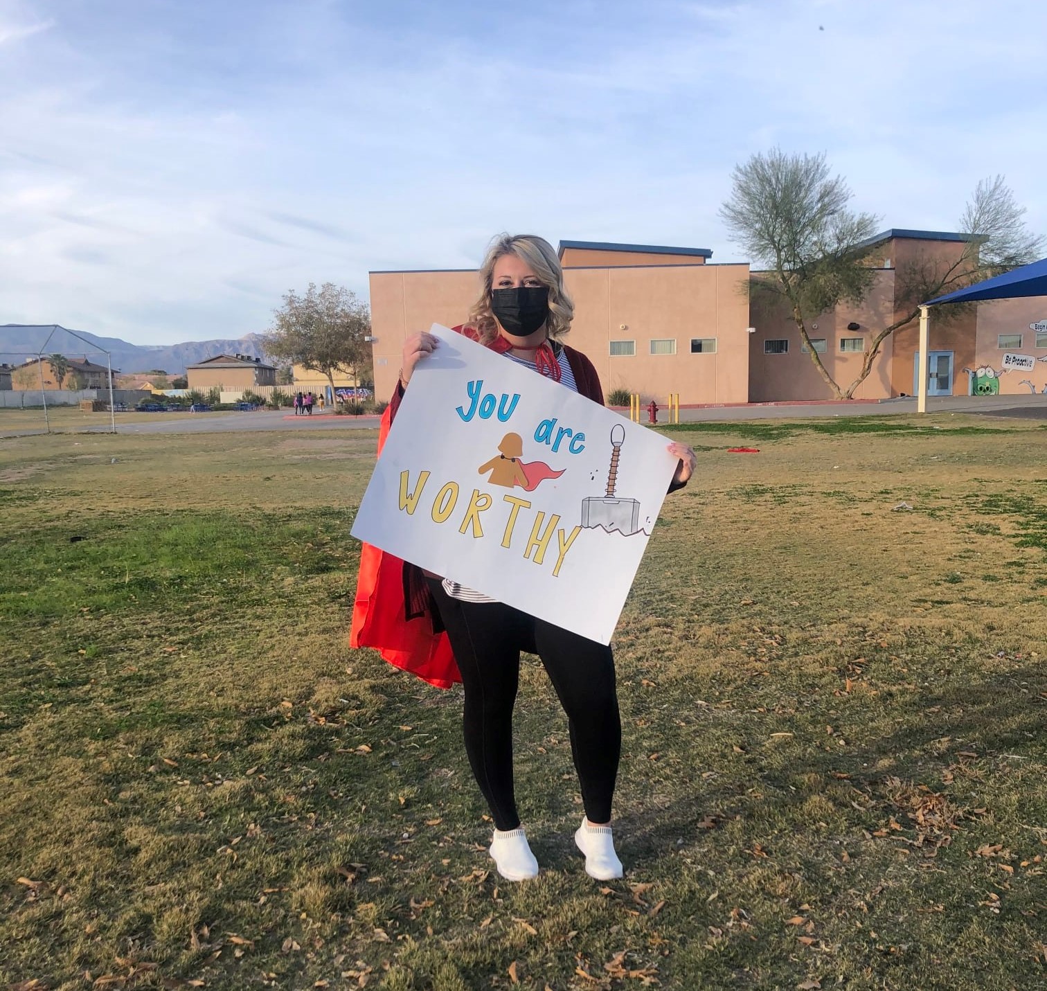 Woman in red cape holding up a fantastic 5K sign that says you are worthy!