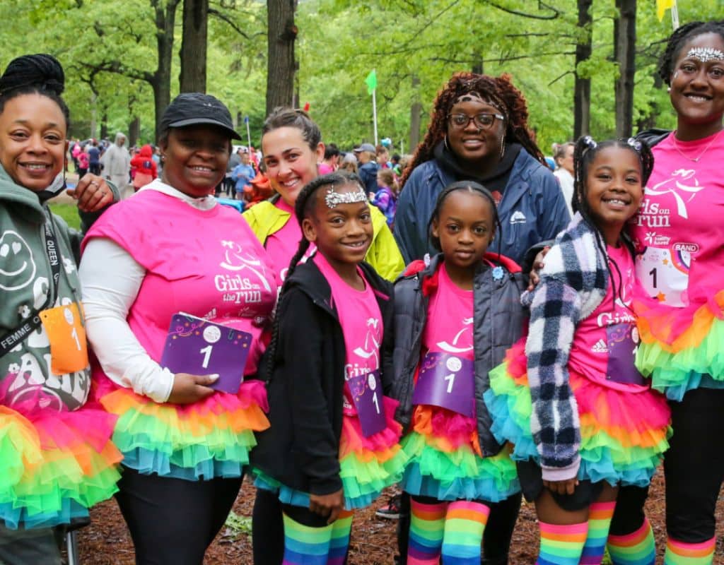 Girls on the Run coaches and participants in rainbow tutus smiling at a 5K Celebration