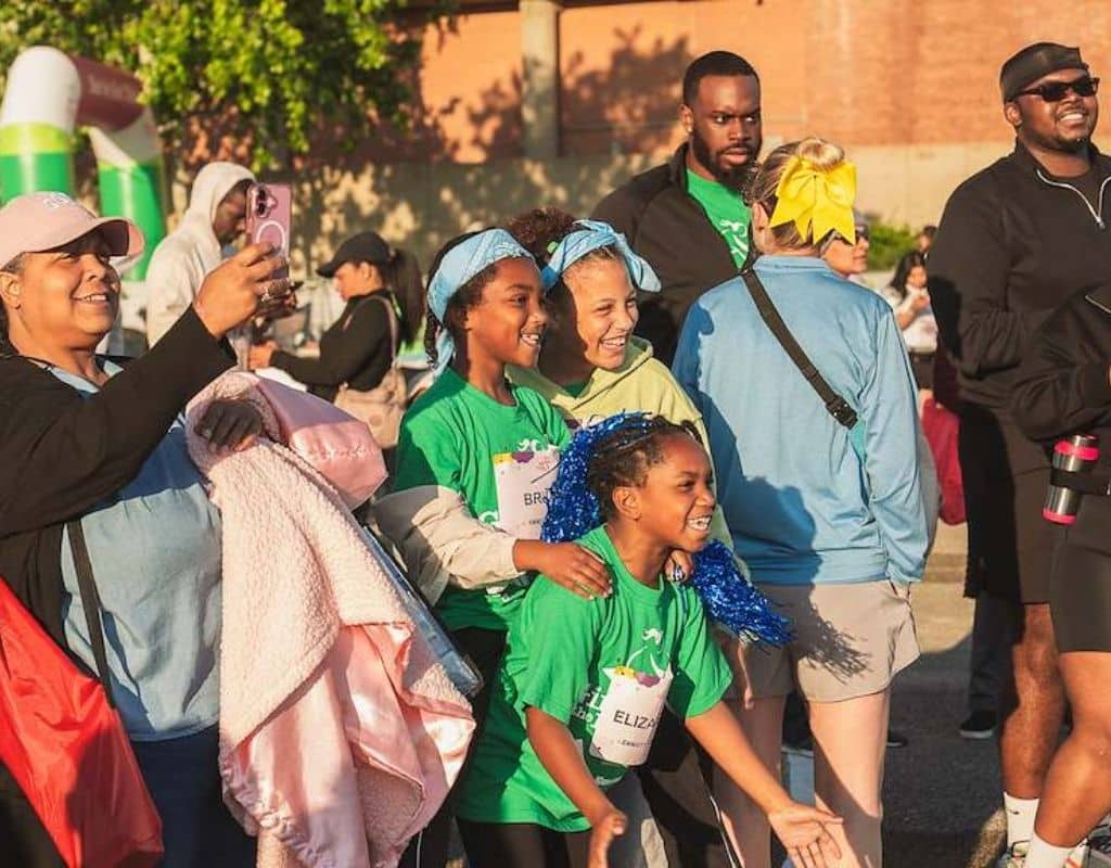 Group of girls in green shirts at the Girls on the Run 5K smiling for a photo together.